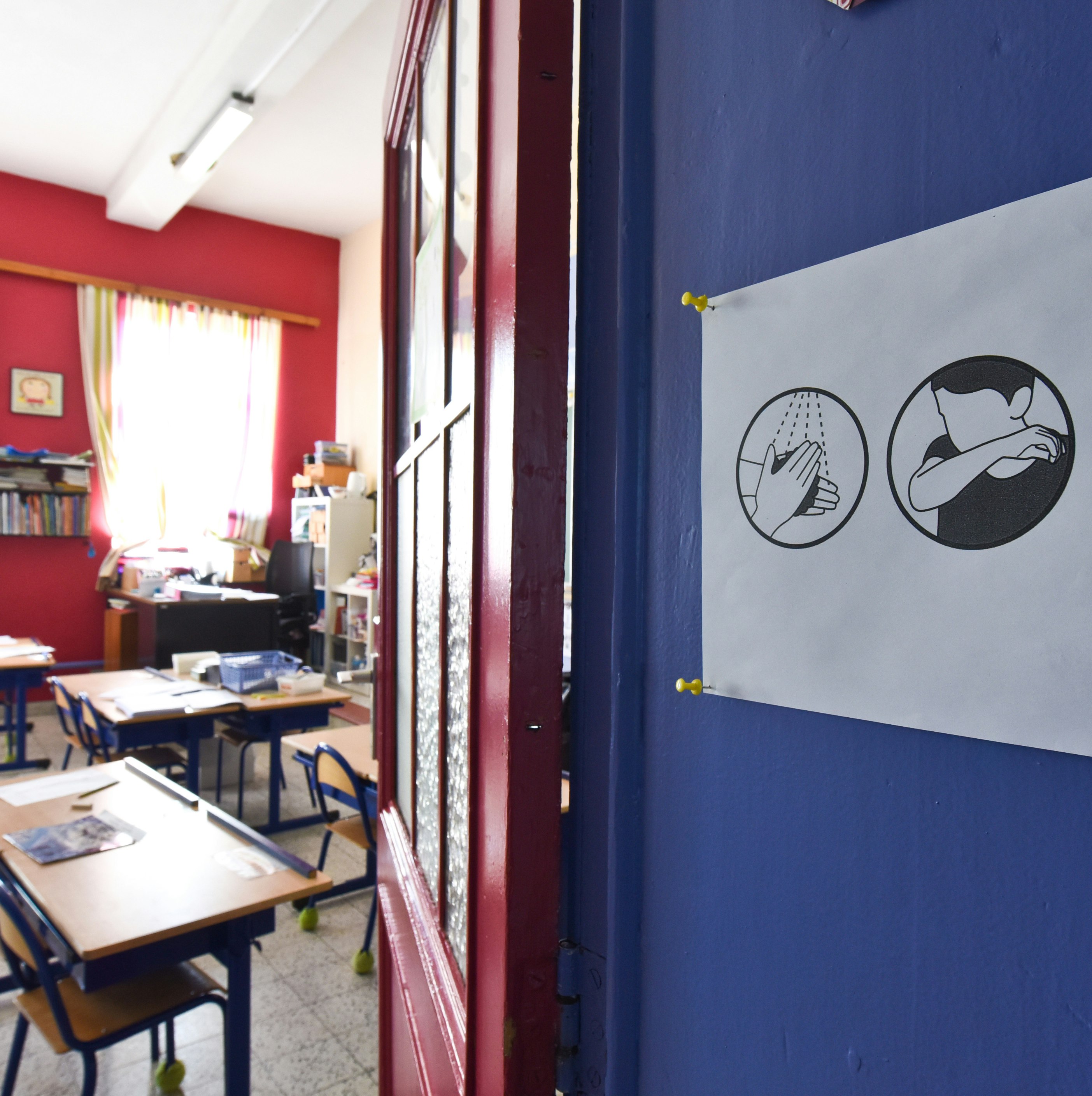 An empty classroom. A sign with instructions on preventing the spread of viruses is posted on the door.