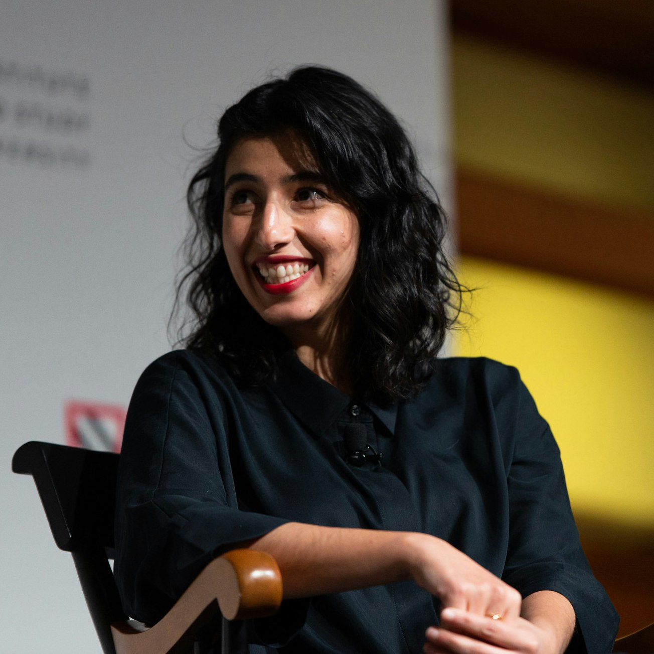 Solmaz Sharif sits on stage and smiles.