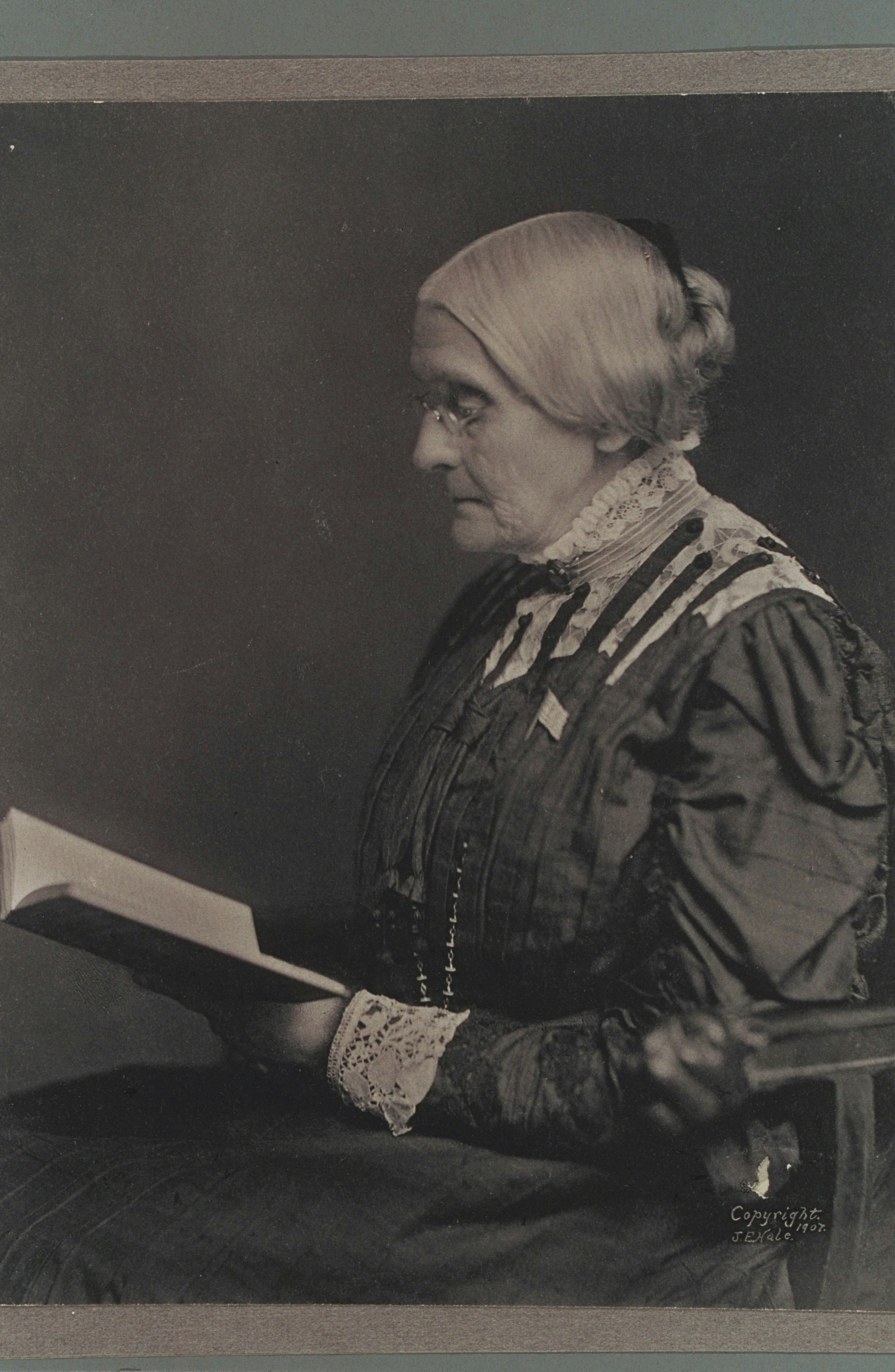 Susan B. Anthony seated, and reading a book