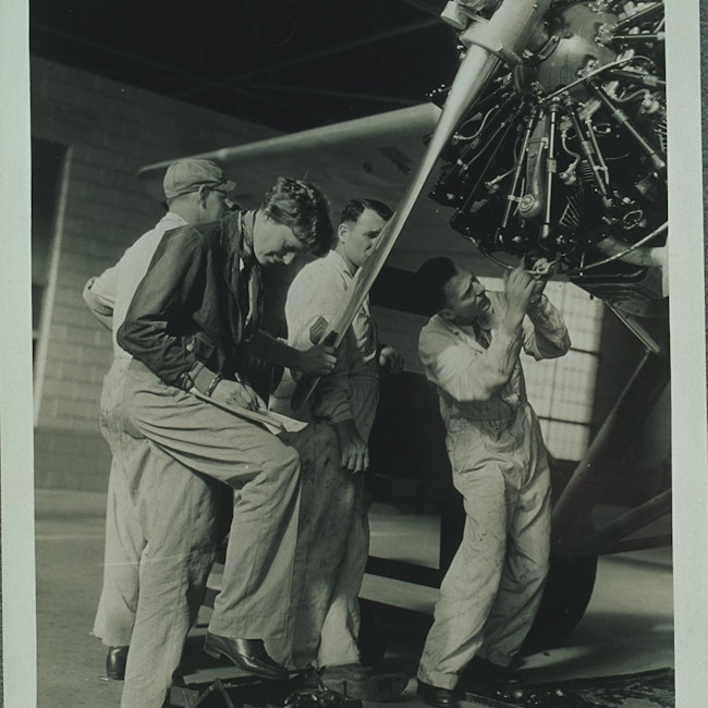 Amelia Earhart and three men checking the propellor of her airplane