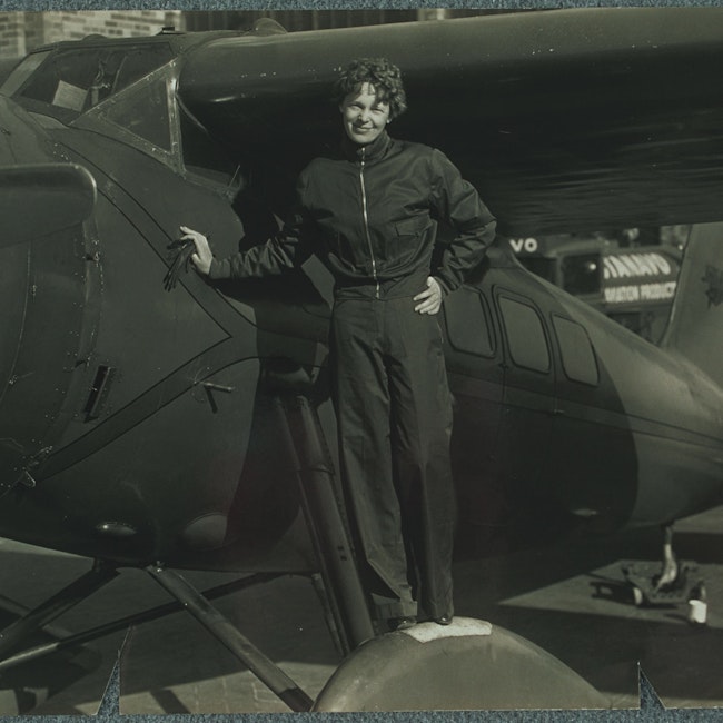 Amelia Earhart standing on the wheel of her airplane, probably the Lockheed "Vega."