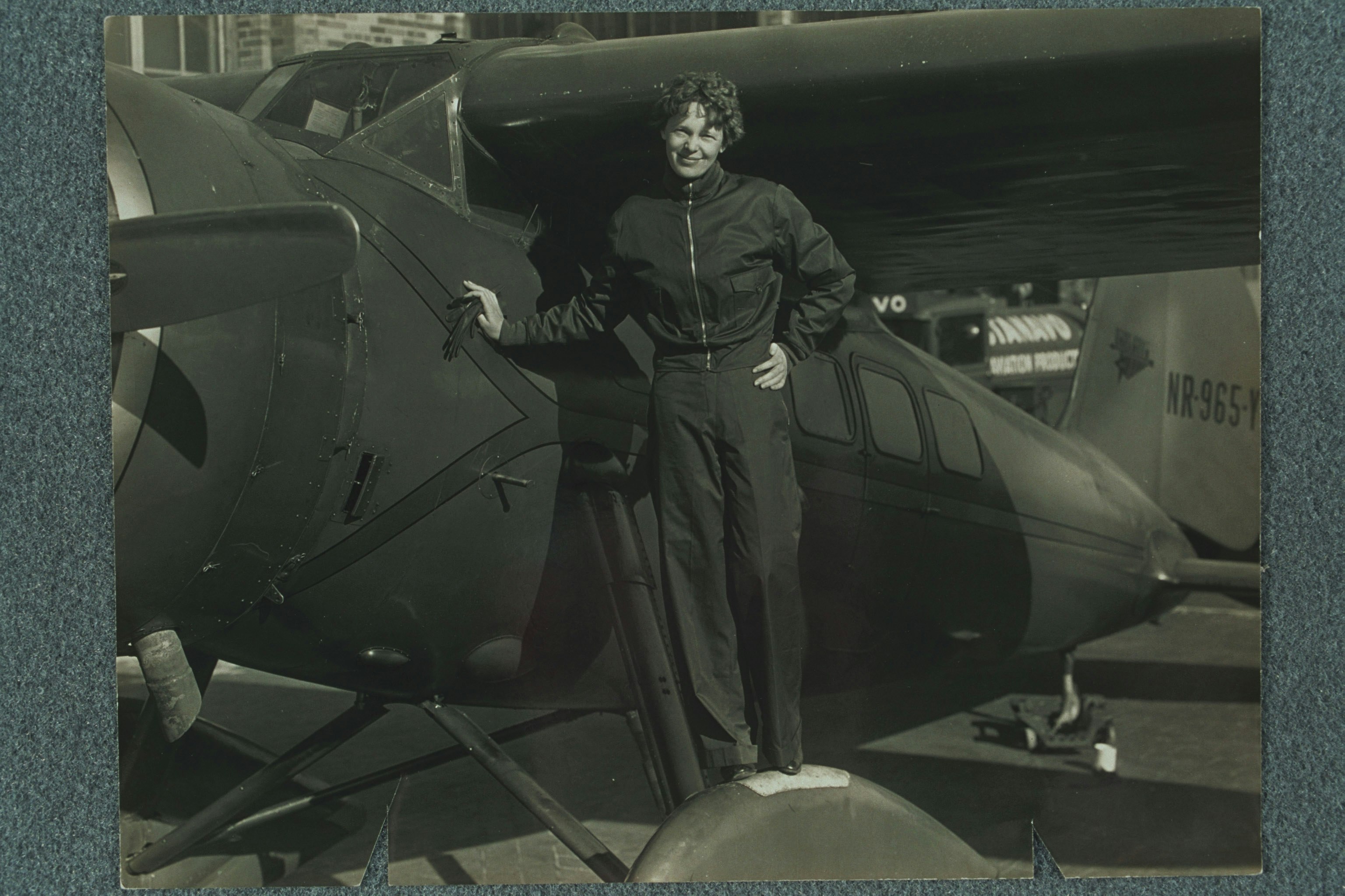 Amelia Earhart standing on the wheel of her airplane, probably the Lockheed "Vega."