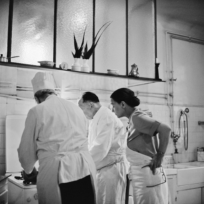 Julia Child and two others working in the kitchen