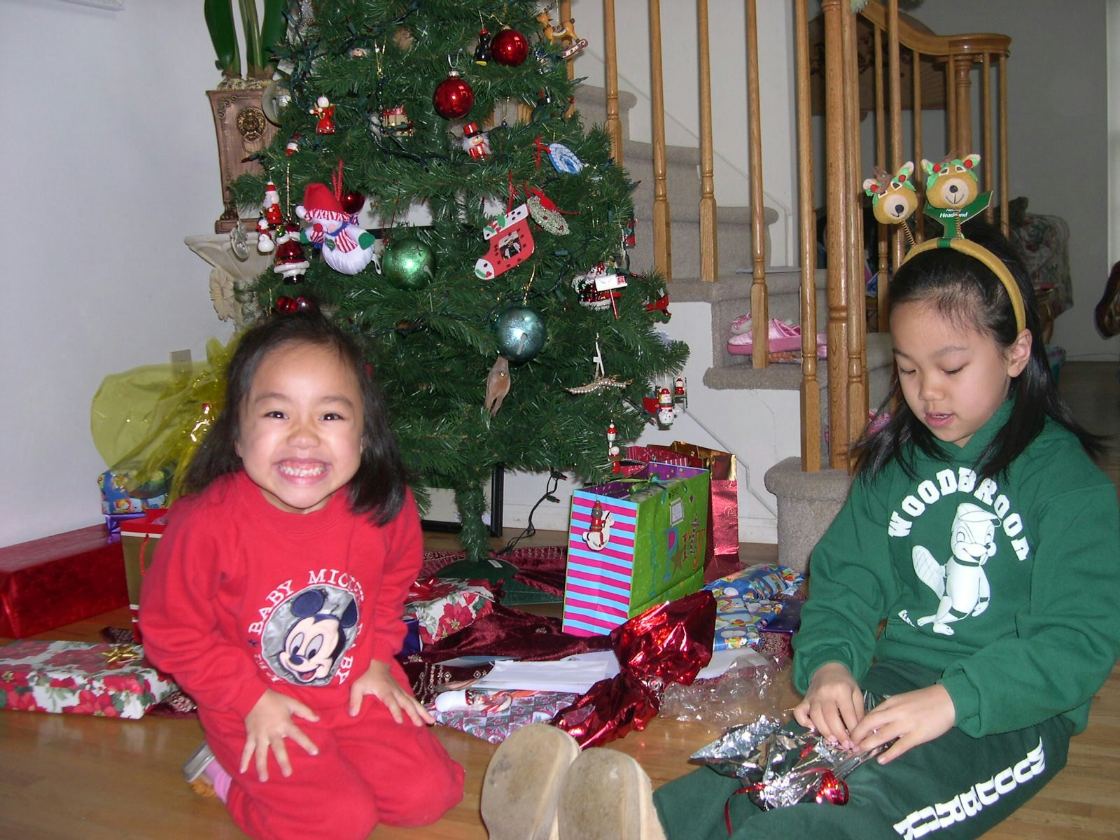 Vanessa Hu and sister sitting around Christmas tree opening gifts