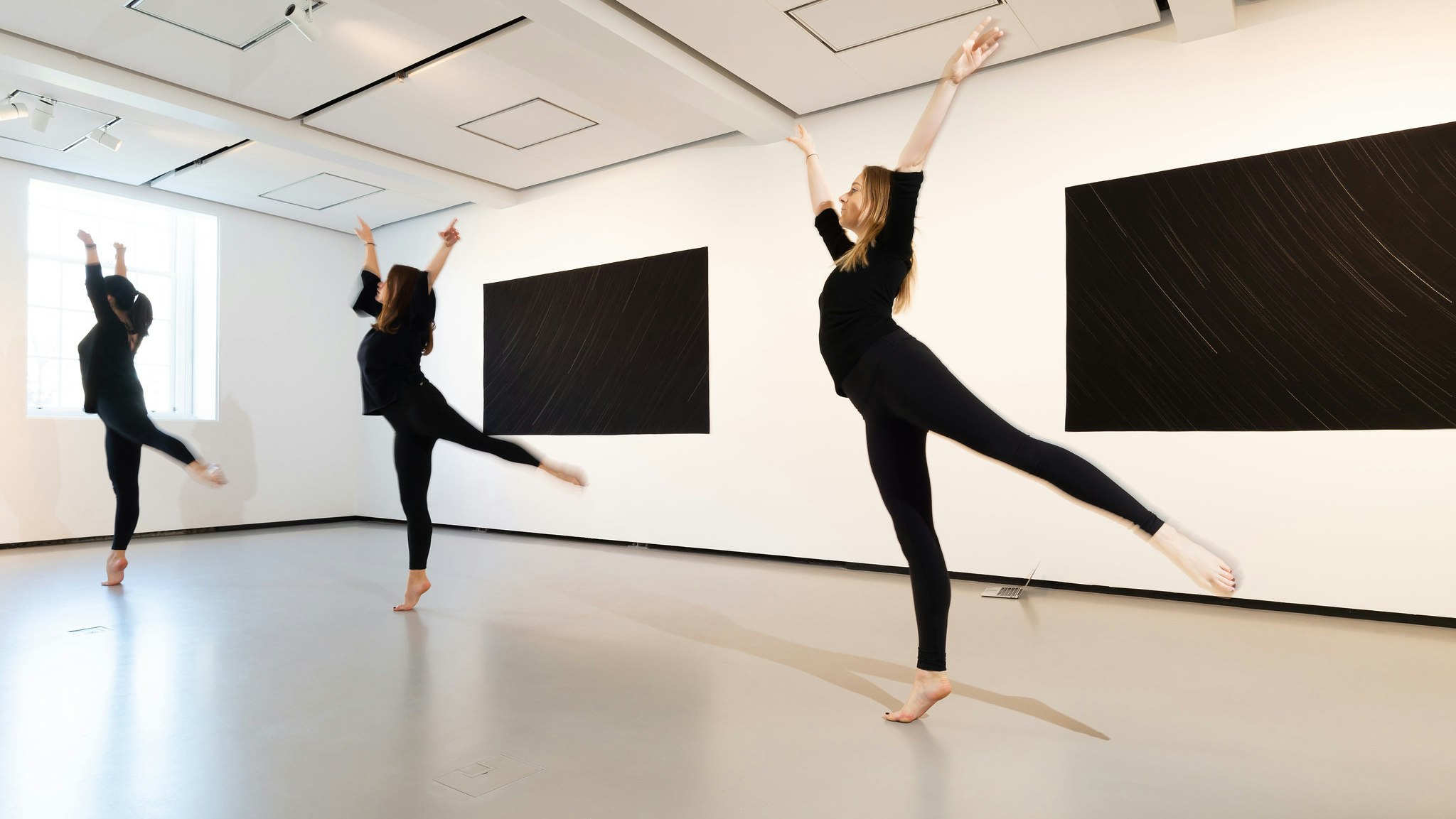 Three ballet dancers perform in a gallery.