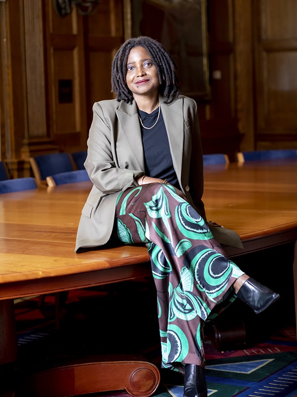 Tracy K. Smith sits smiling atop a conference table, legs crossed.