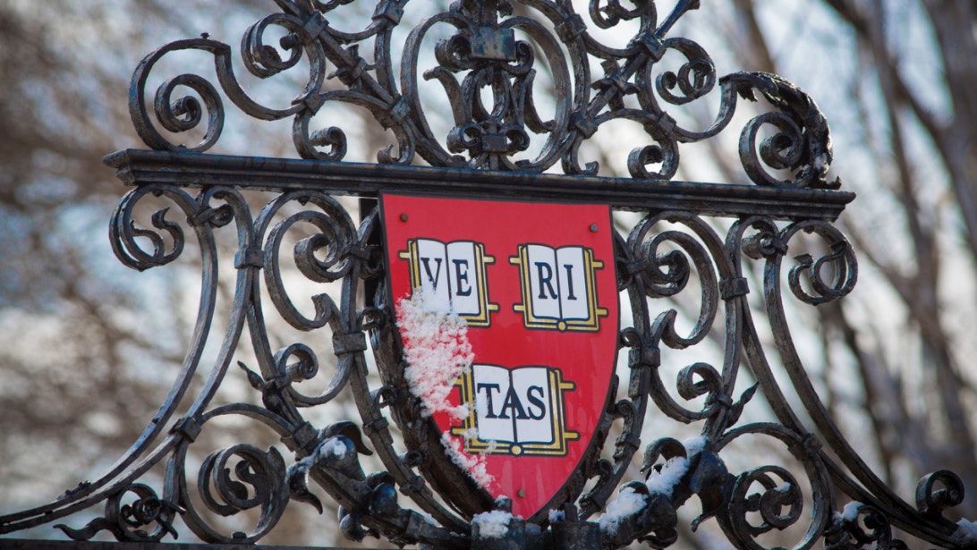The Harvard shield, featuring the word Veritas, on an ornate iron gate.