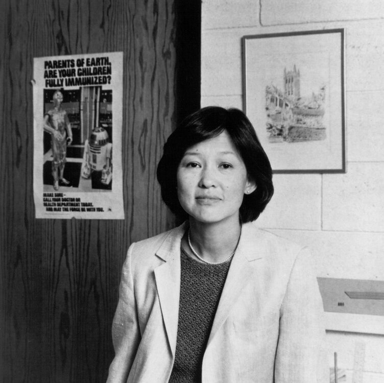 Black & White image of Alice Huang in business dress suit in what appears to be a classroom or office
