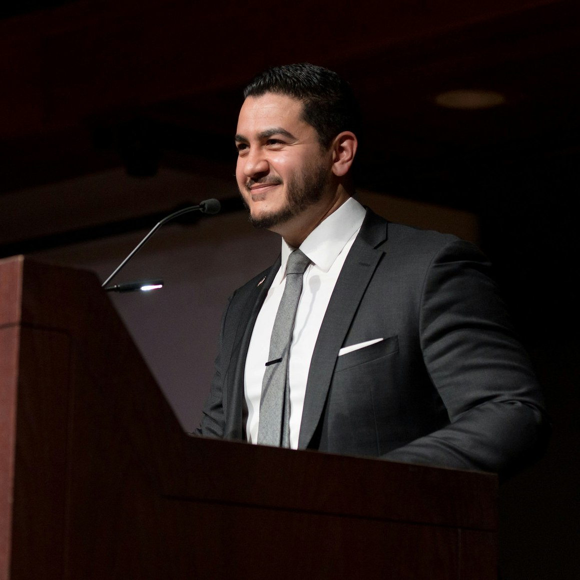 Abdul El-Sayed stands at a podium smiling.
