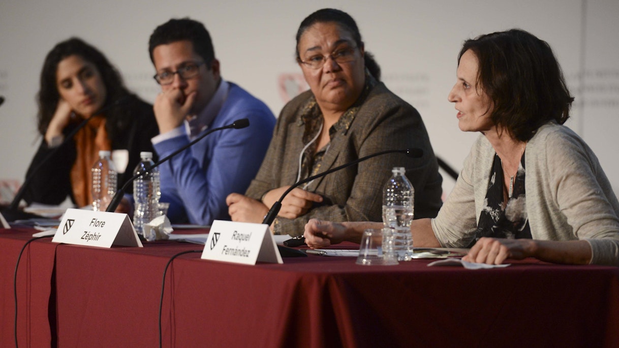 Natasha Kumar Warikoo, Roberto G. Gonzales, Flore Zéphir, and Raquel Fernández sit at a panel table. Raquel Fernández is speaking while the others listen.