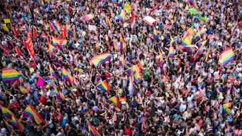 Crowd of demonstators, many waving rainbow flags