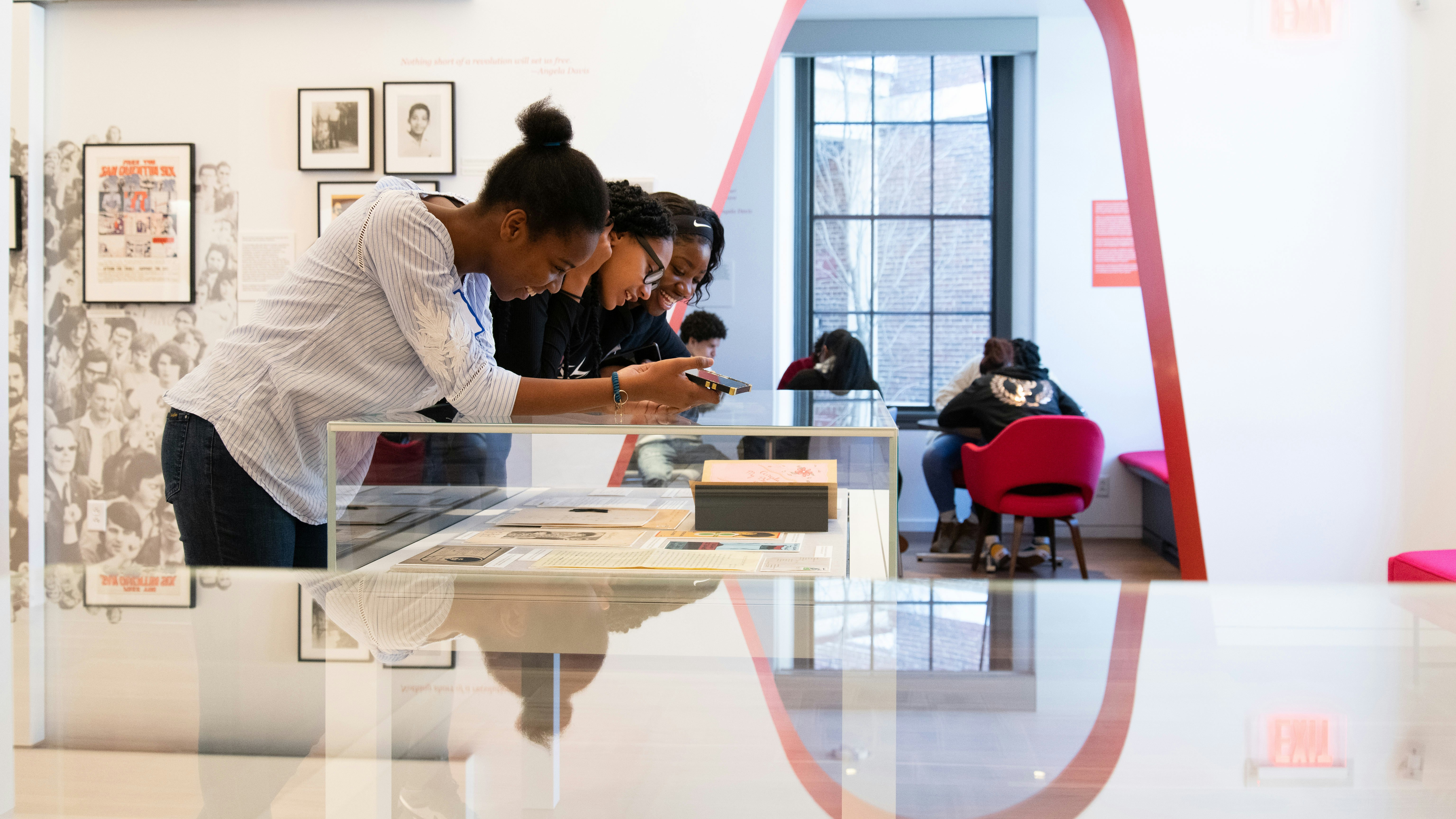 Three high school students look at a glass case that contains items from the papers of Angela Davis.