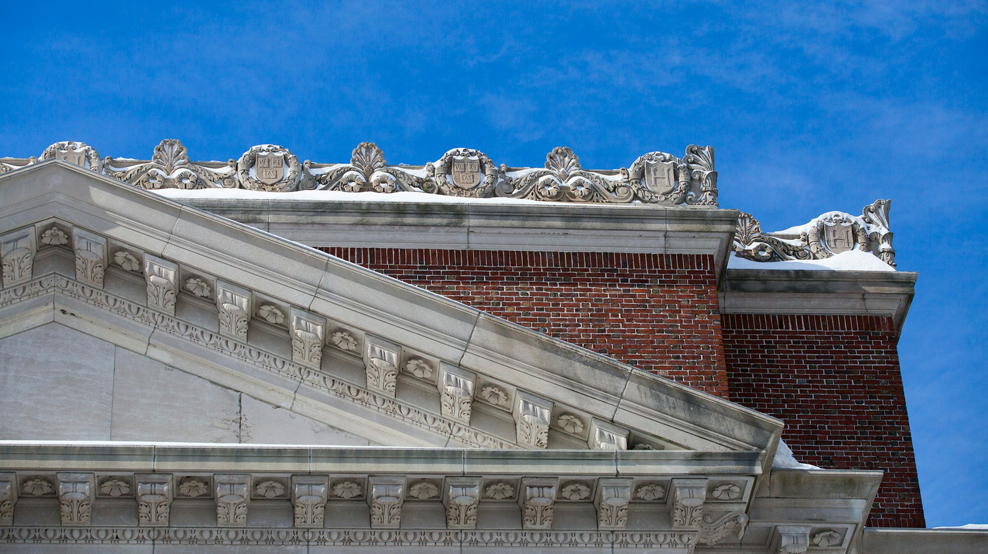 stone roofline with repeating motif of Harvard shield