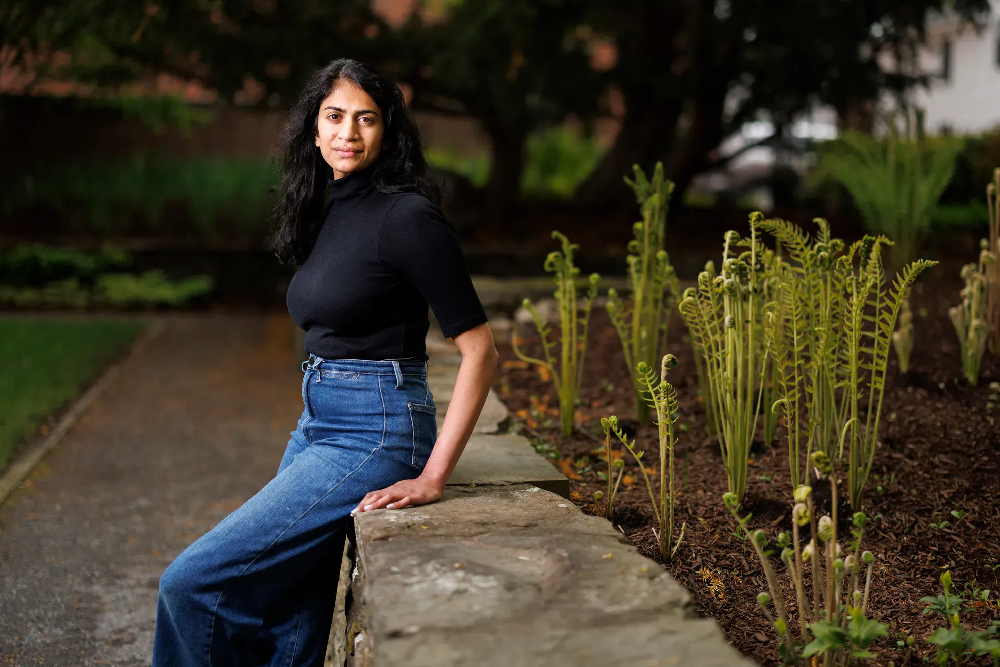 Rachna Reddy leaning on a low outdoor garden wall