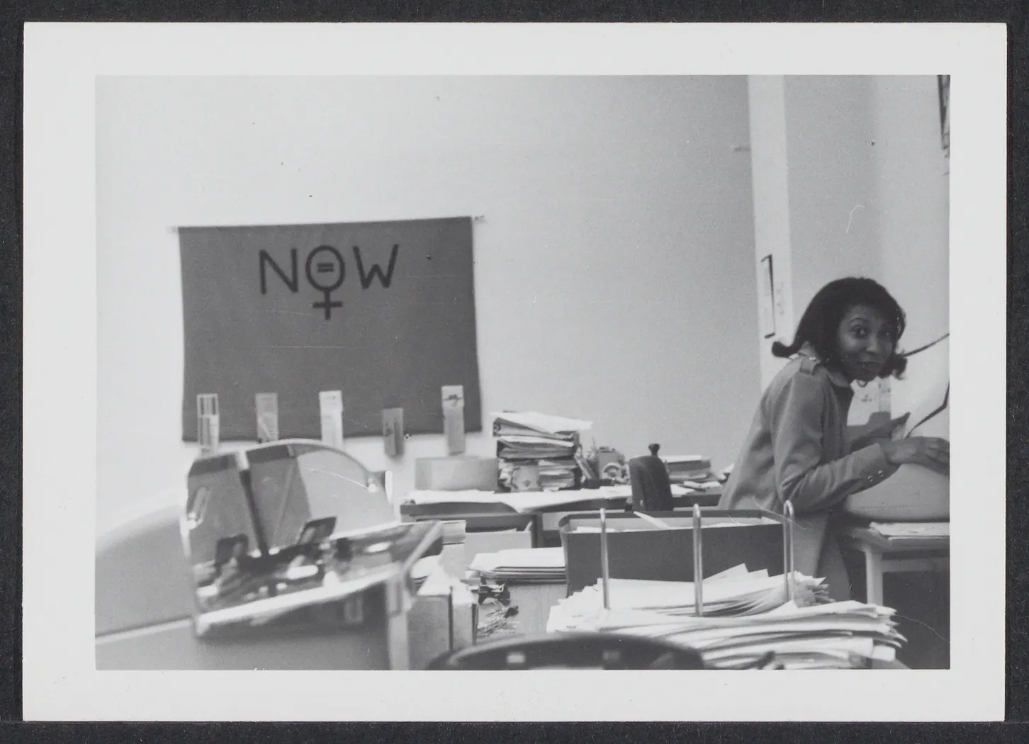 A historical photo of a smiling woman at work in an office