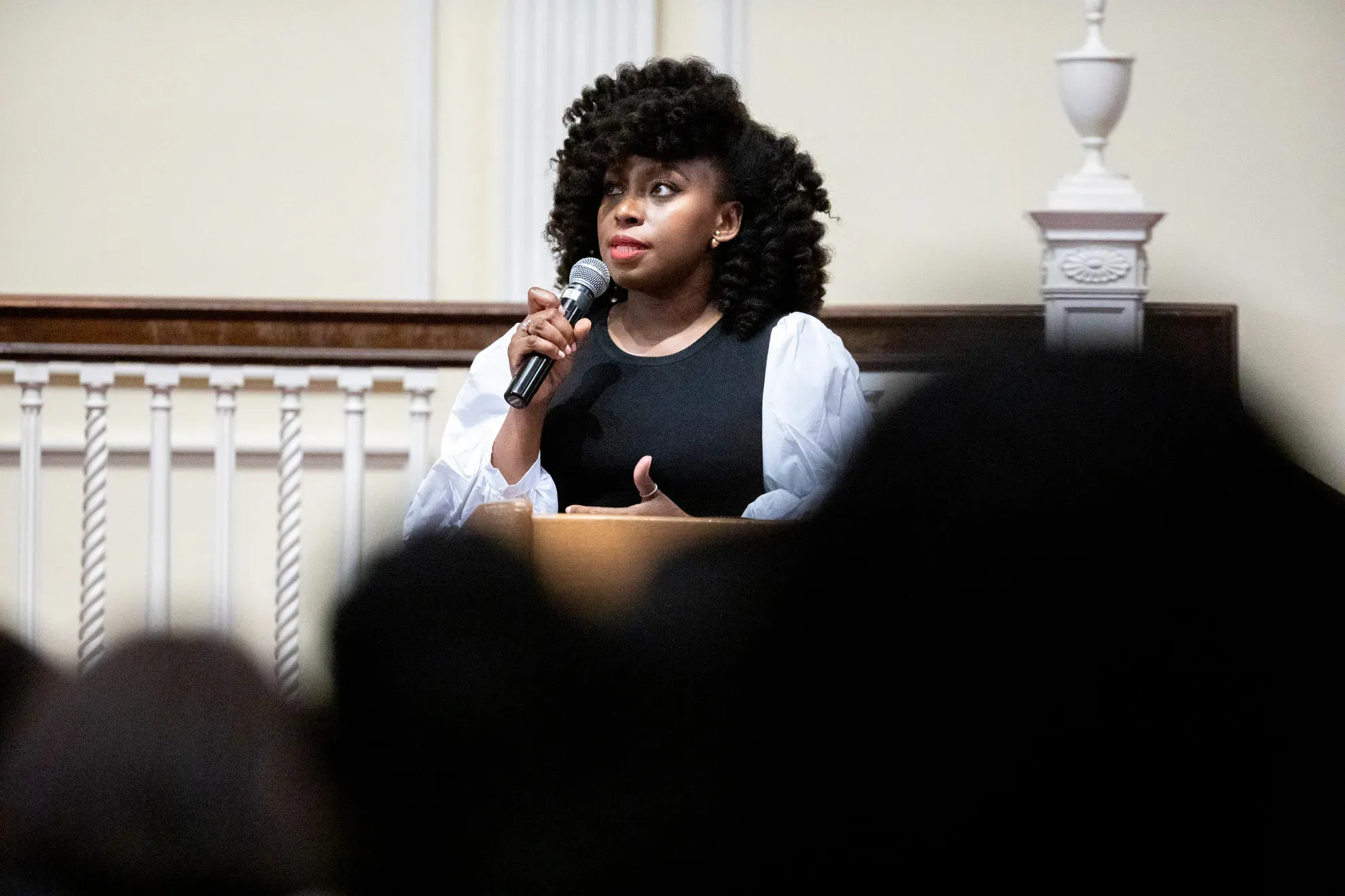 0A Black woman speaks into a microphone in front of a crowd