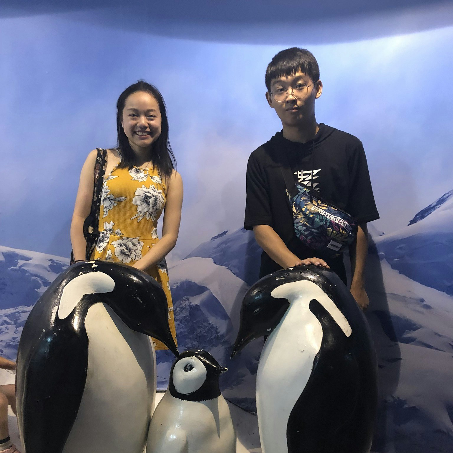 Vanessa Hu and cousin sitting on penguin sculptures at the Shanghai aquarium