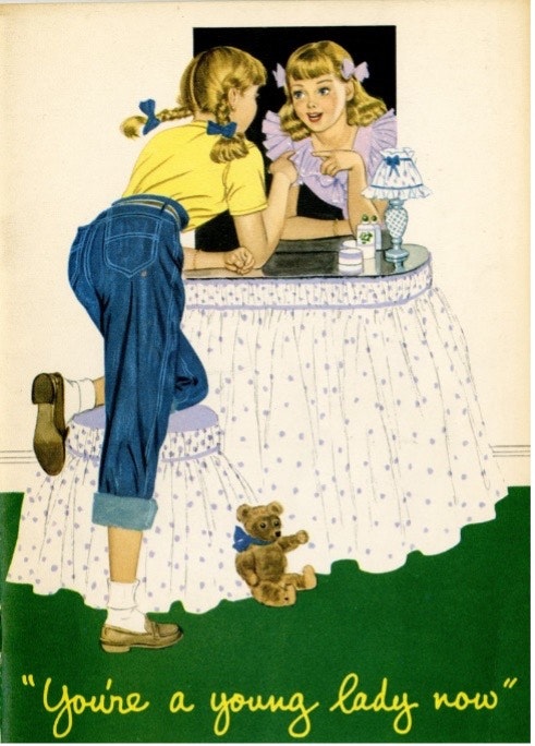 An illustration of a blond girl in pigtails, wearing a yellow shirt and dungarees, looking in the mirror of a skirted vanity. In the reflection, she wears a lavender dress, and her hair is down, pulled back from her face with matching ribbons. Tagline reads "You're a young lady now."
