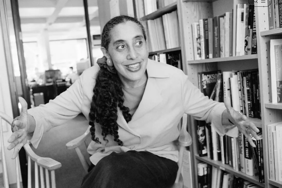 Black and white image of Lani Guinier sitting down and speaking in from of a book shelf