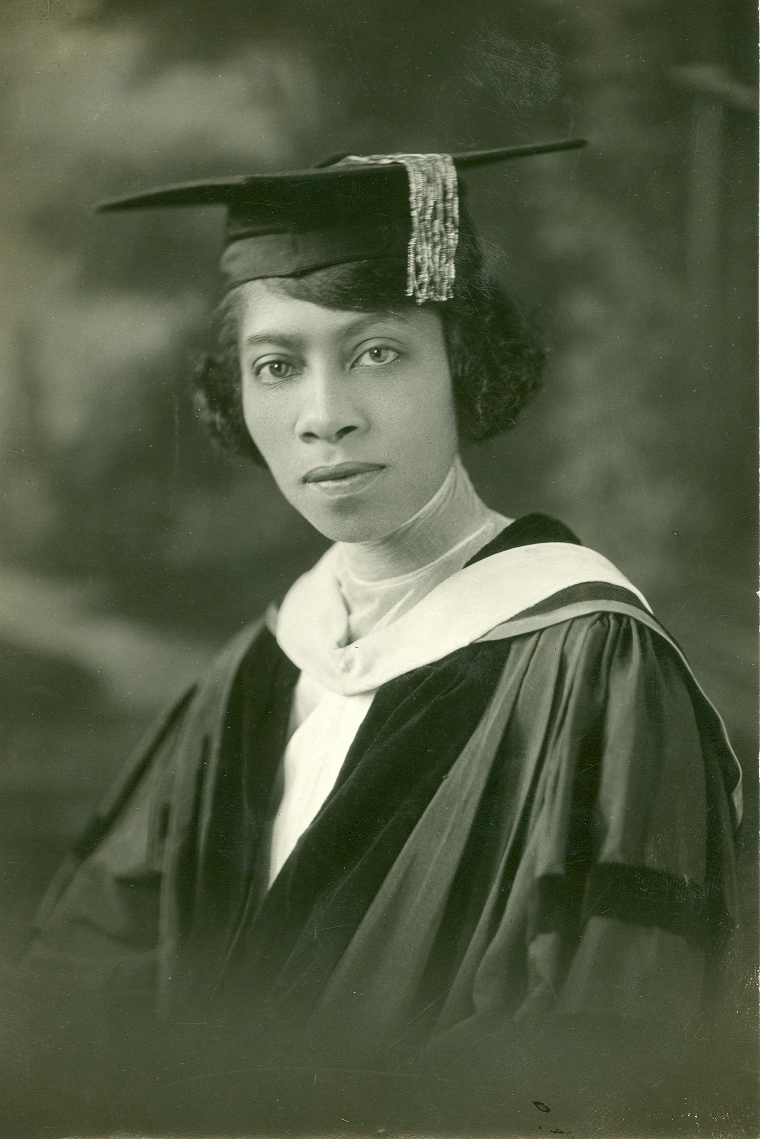 Black-and-white portrait of Eva B. Dykes at graduation: bust portrait in three quarter profile of a young woman in academic robe and cap.