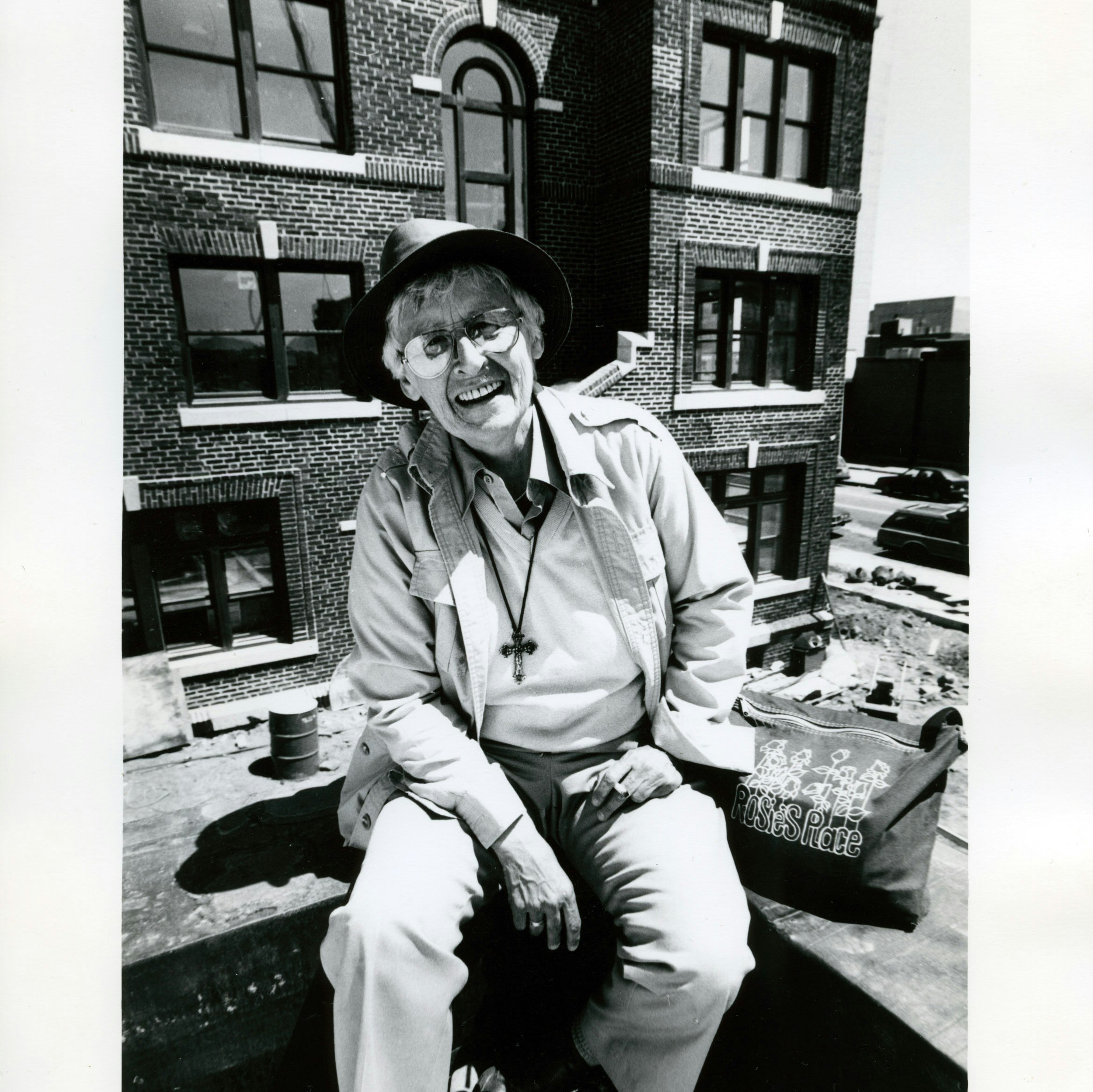 Kip Tierman smiling, and seated outdoors on a rooftop, ca. 1991.
