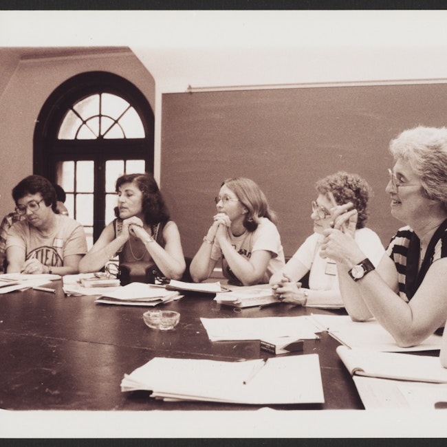 Gerda Lerner with 5 women seated at a classroom table, possibly at a conference