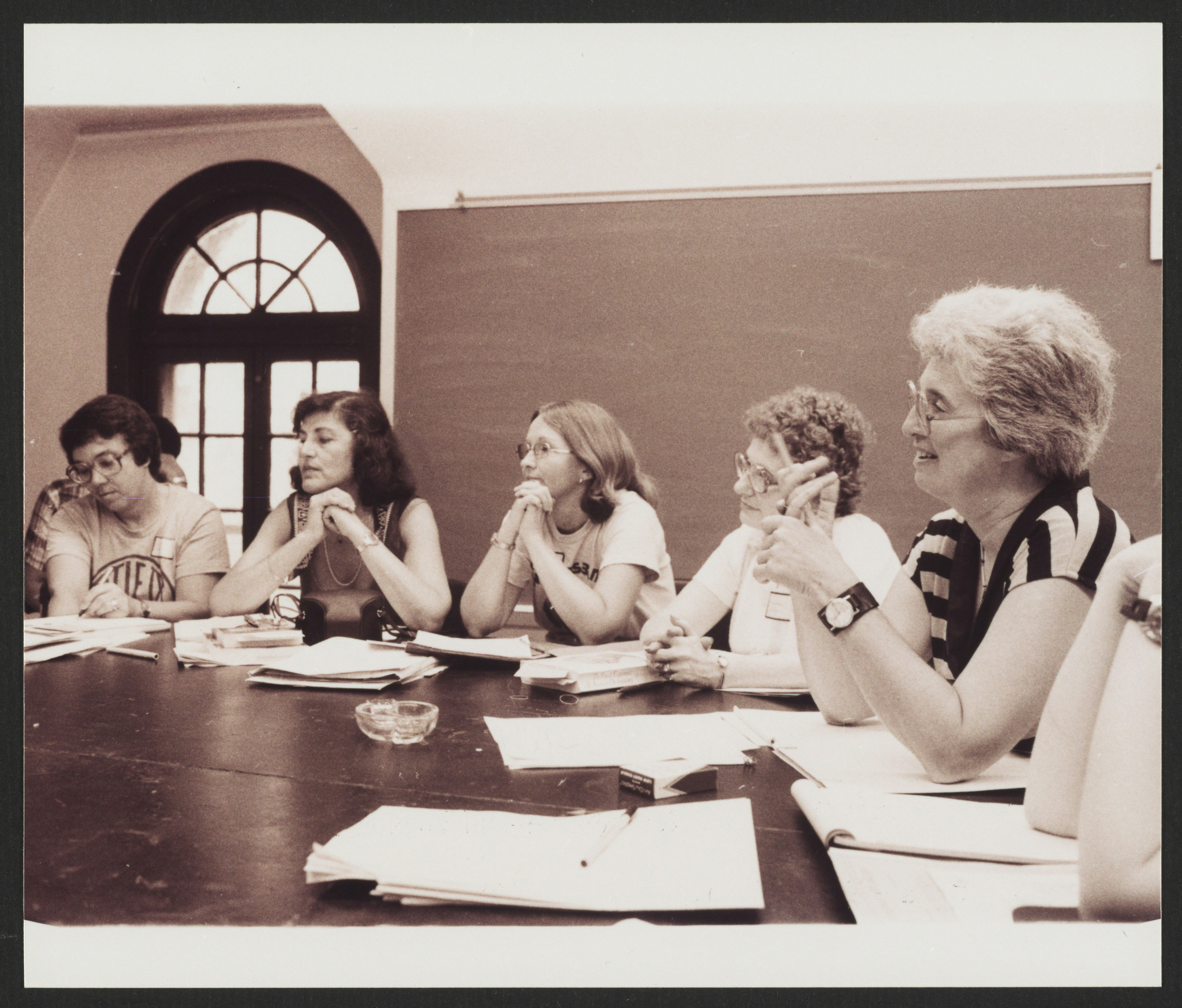 Gerda Lerner with 5 women seated at a classroom table, possibly at a conference
