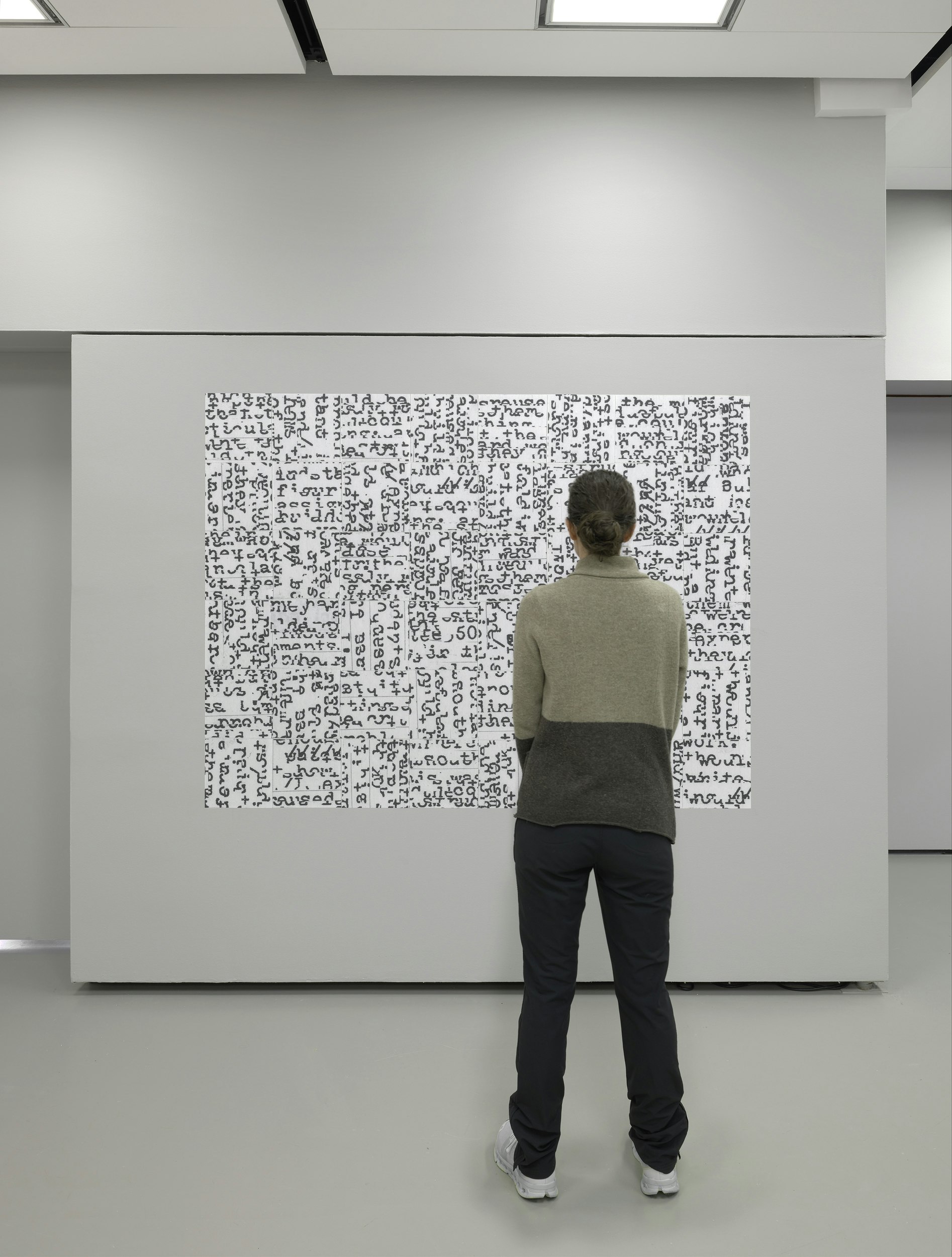 A person stands in front of a vinyl collage, contemplating the artwork.