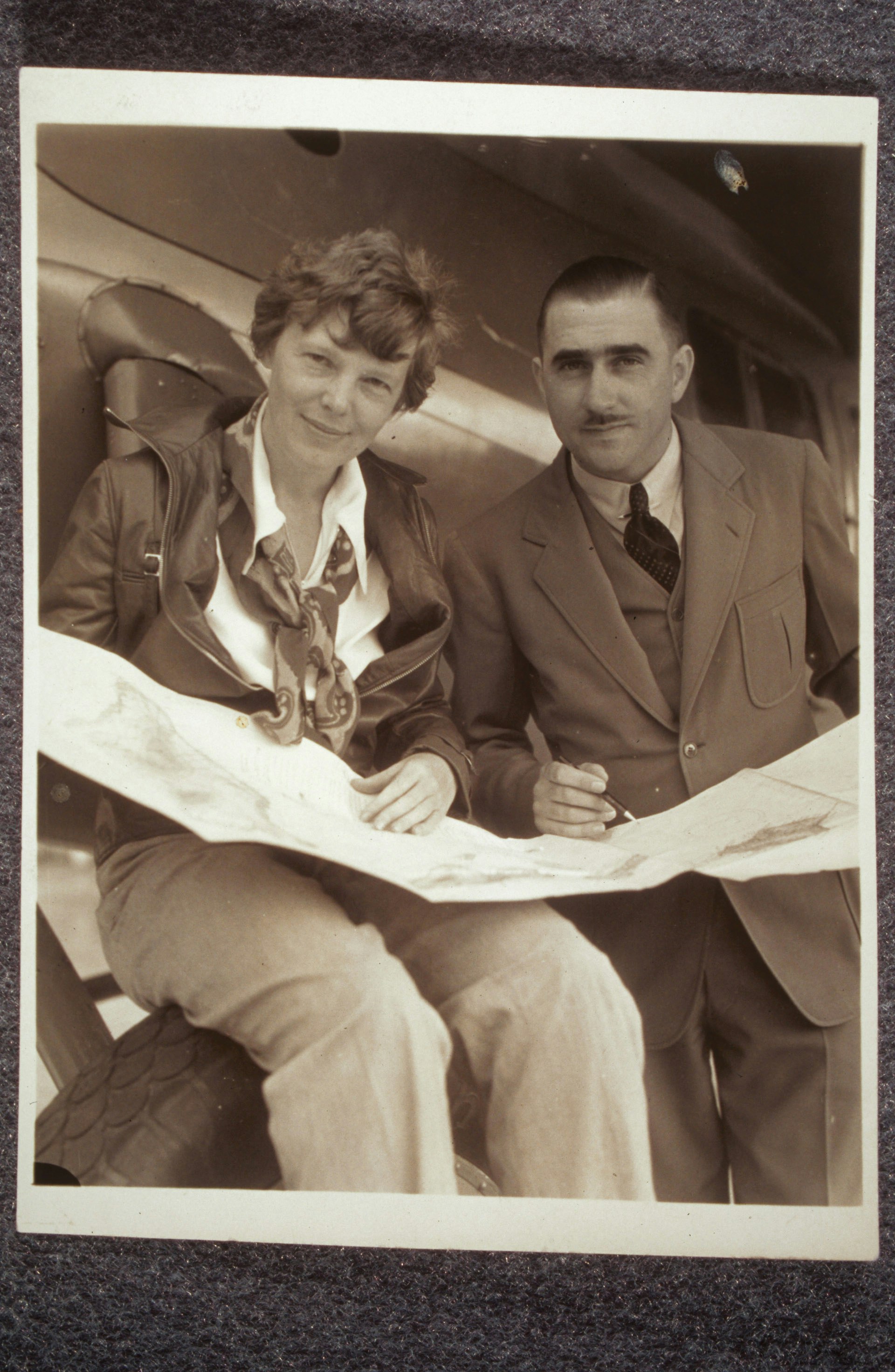 Amelia Earhart and Paul Mantz looking at a flight chart or map together