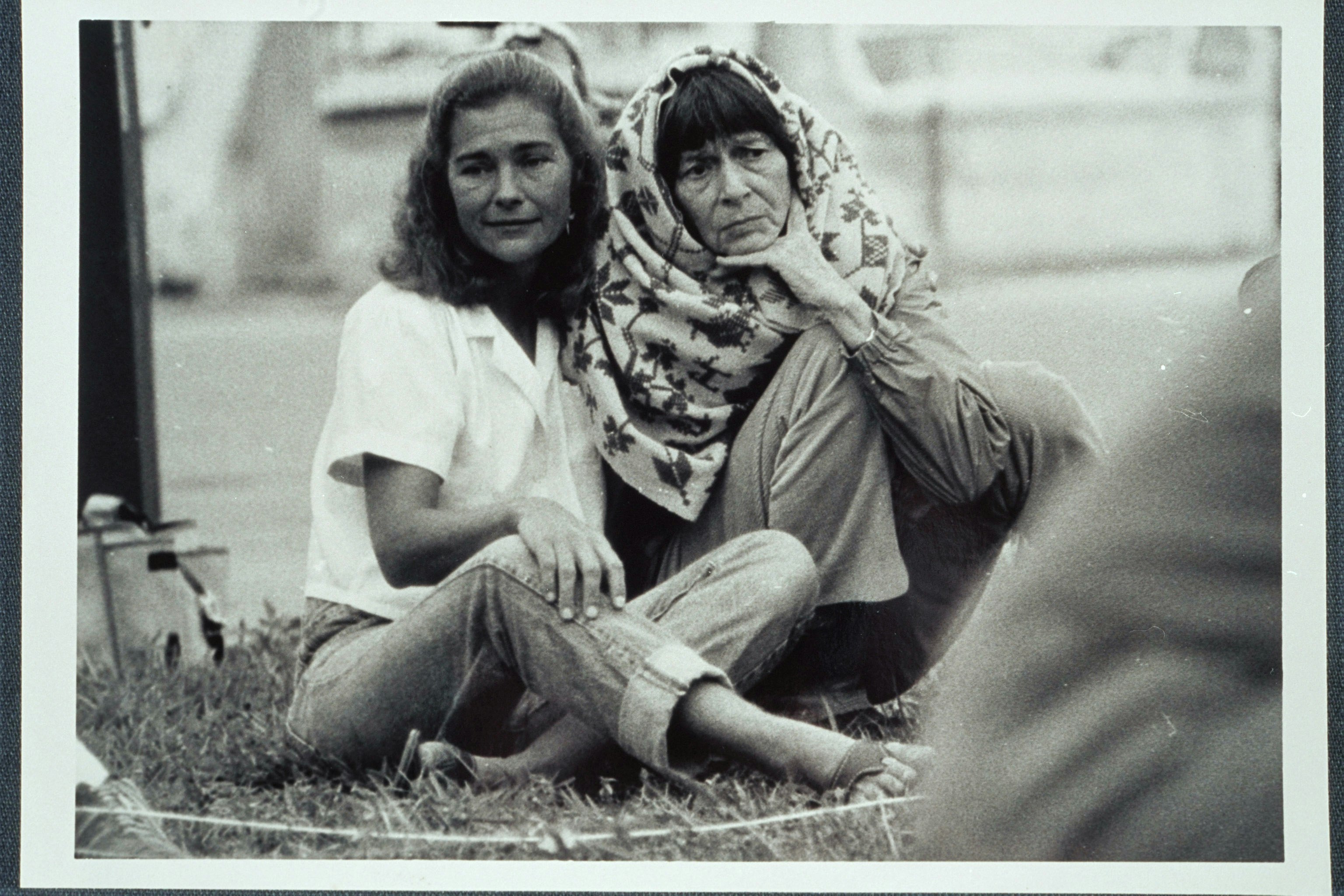 Barbara Deming, wrapped in a shawl, and an unidentified woman seated on the ground
