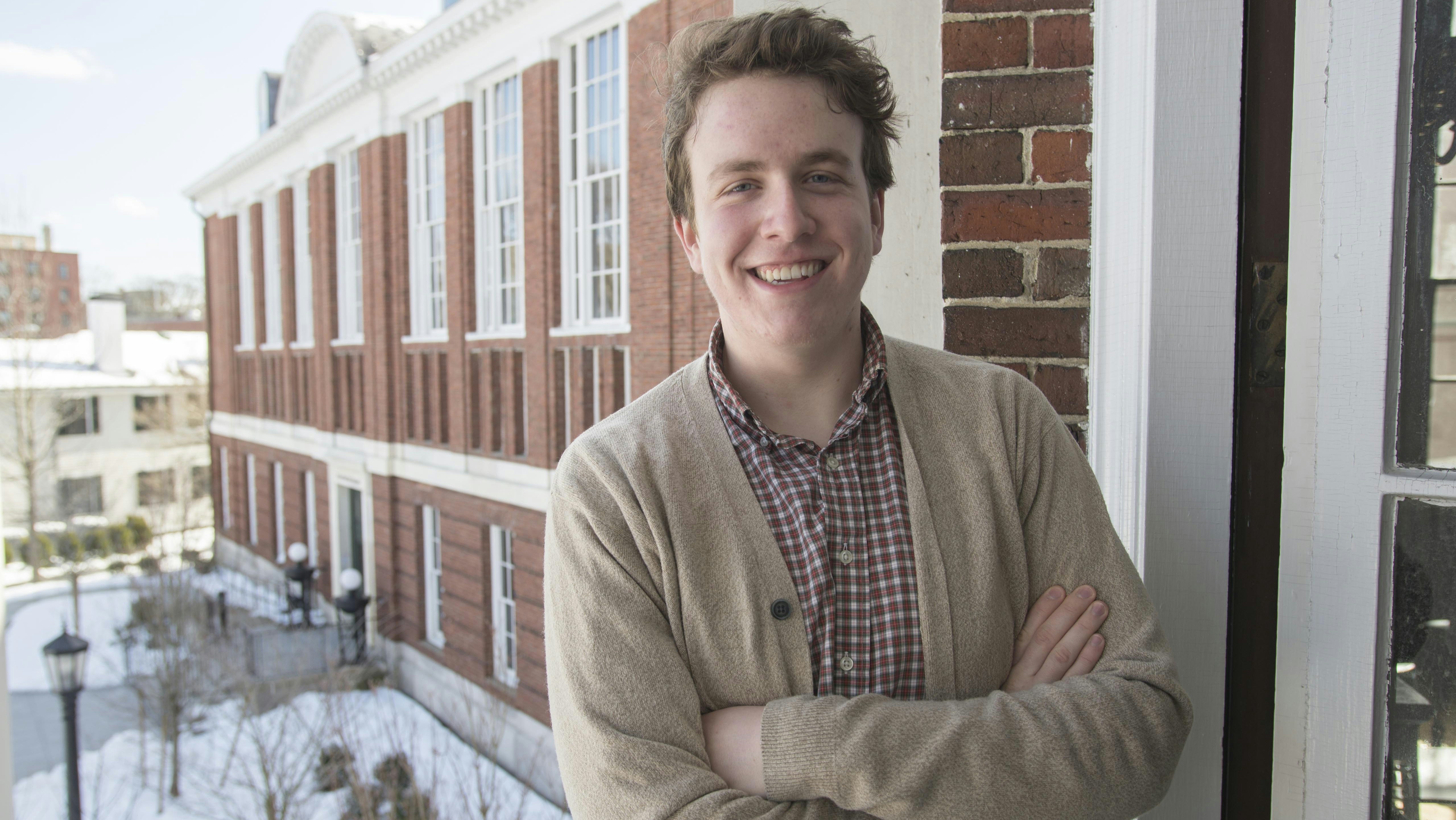 William Simmons '14, arms crossed and smiling, with the Schlesinger Library in the background