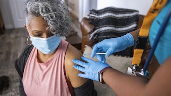 Nurse giving a Covid-19 vaccine to a senior Black woman.