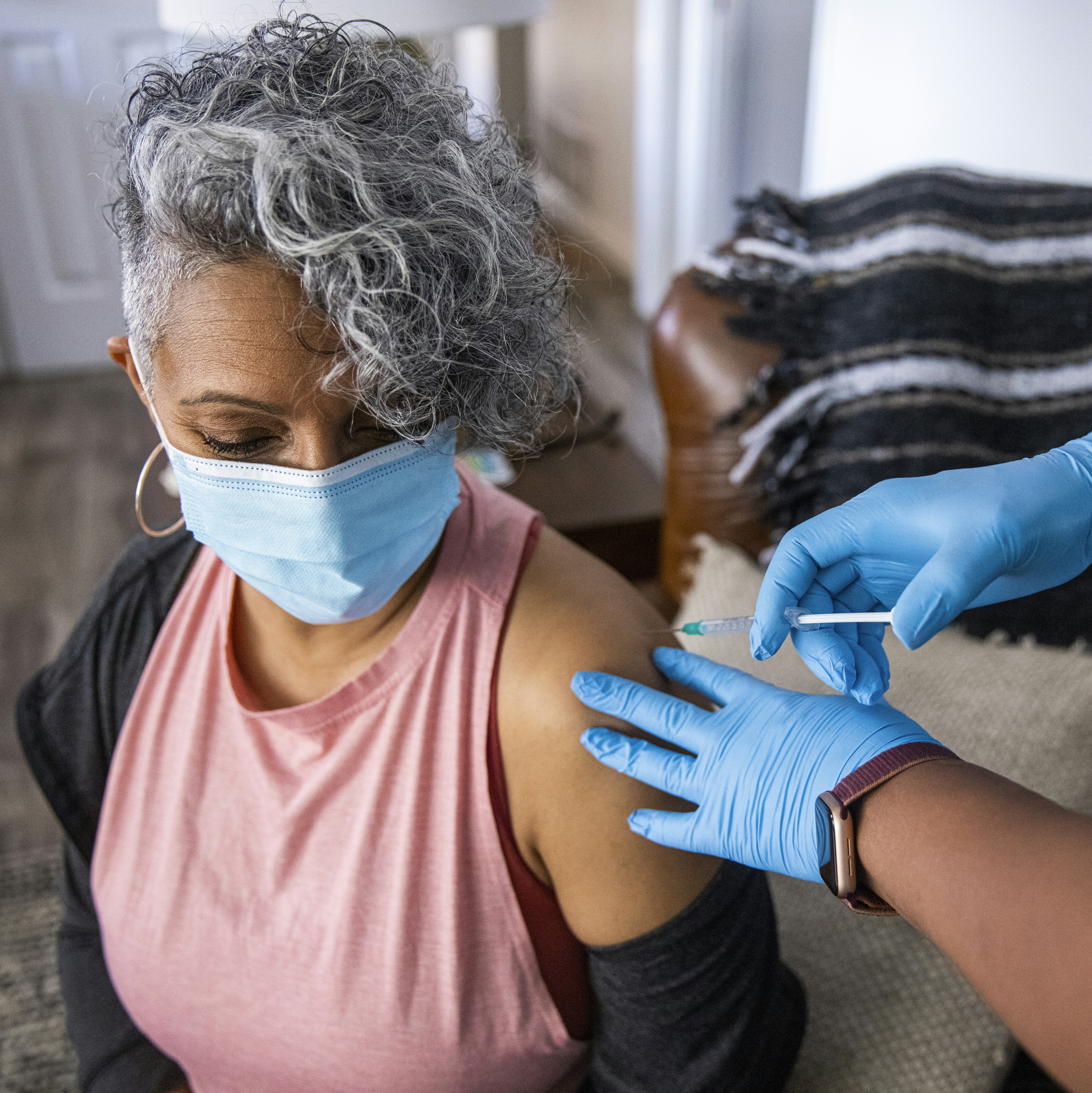 Nurse giving a Covid-19 vaccine to a senior Black woman.