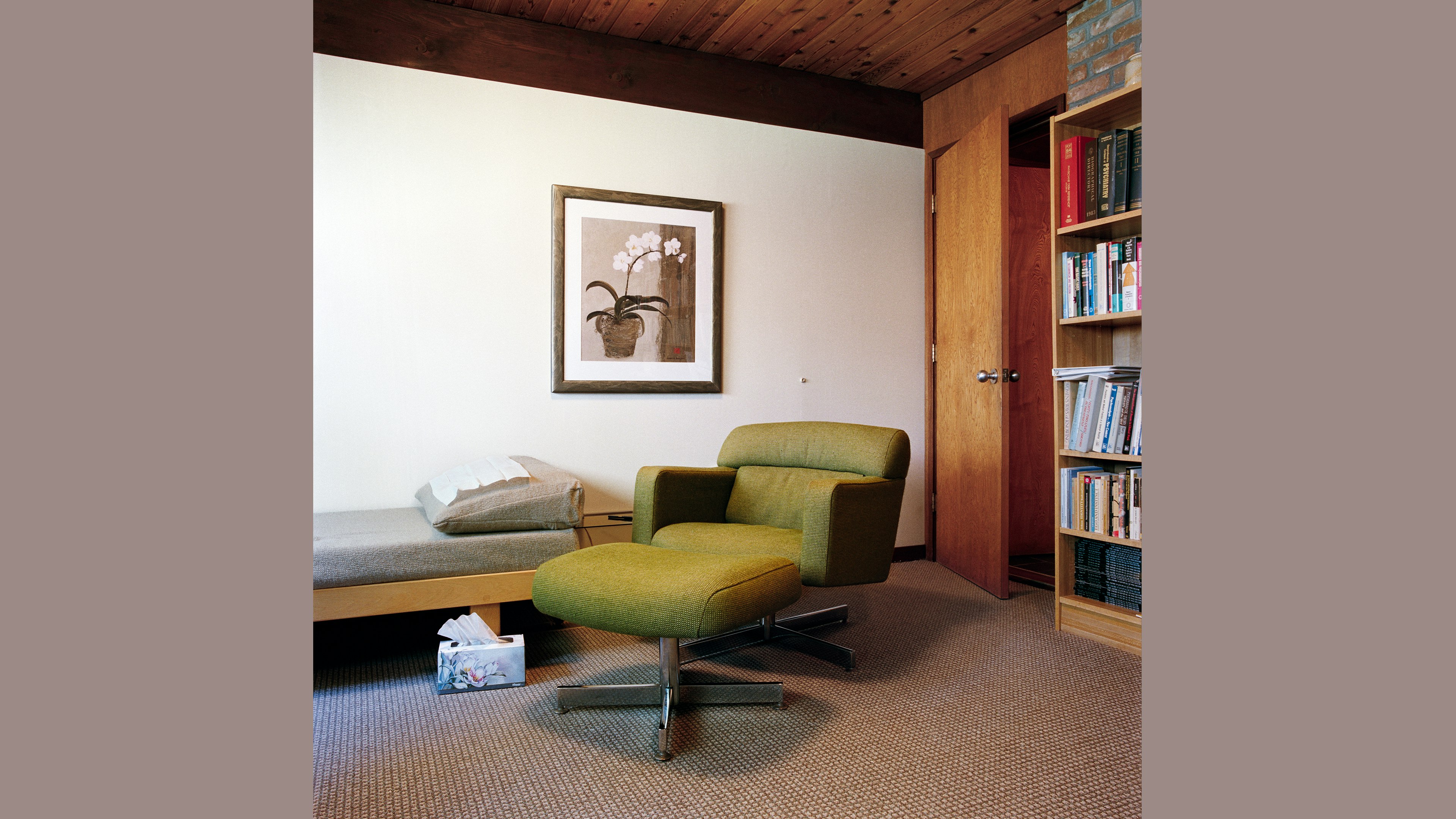A therapists's office with a daybed, a midcentury modern chair, and a box of tissues